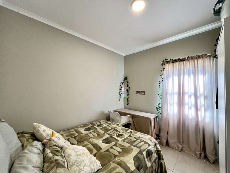 A functional bedroom featuring tiled flooring, neutral wall tones, and a built-in wardrobe, offering a comfortable and well-lit living space.