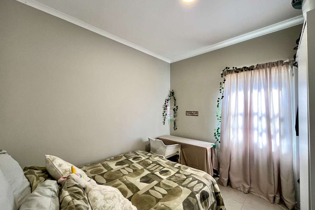 A functional bedroom featuring tiled flooring, neutral wall tones, and a built-in wardrobe, offering a comfortable and well-lit living space.