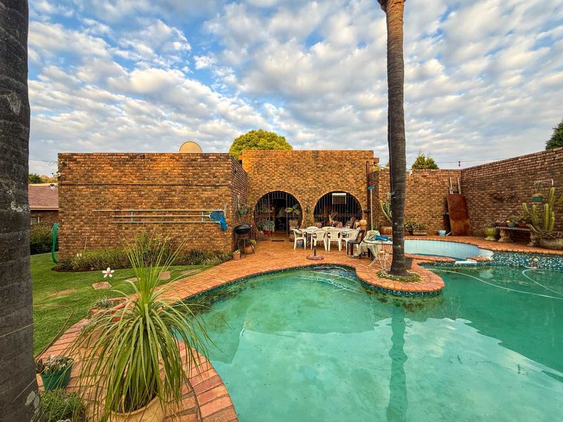 Outdoor pool area featuring a swimming pool with brick surround, exposed brick walls, and arched architectural details.