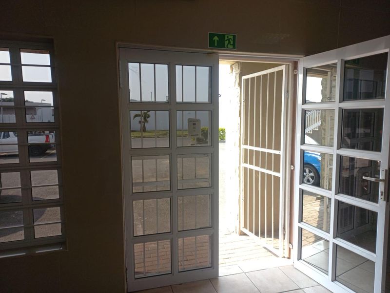 Entrance area featuring glass panelled doors, security gate, and tiled flooring, providing direct access to the exterior.