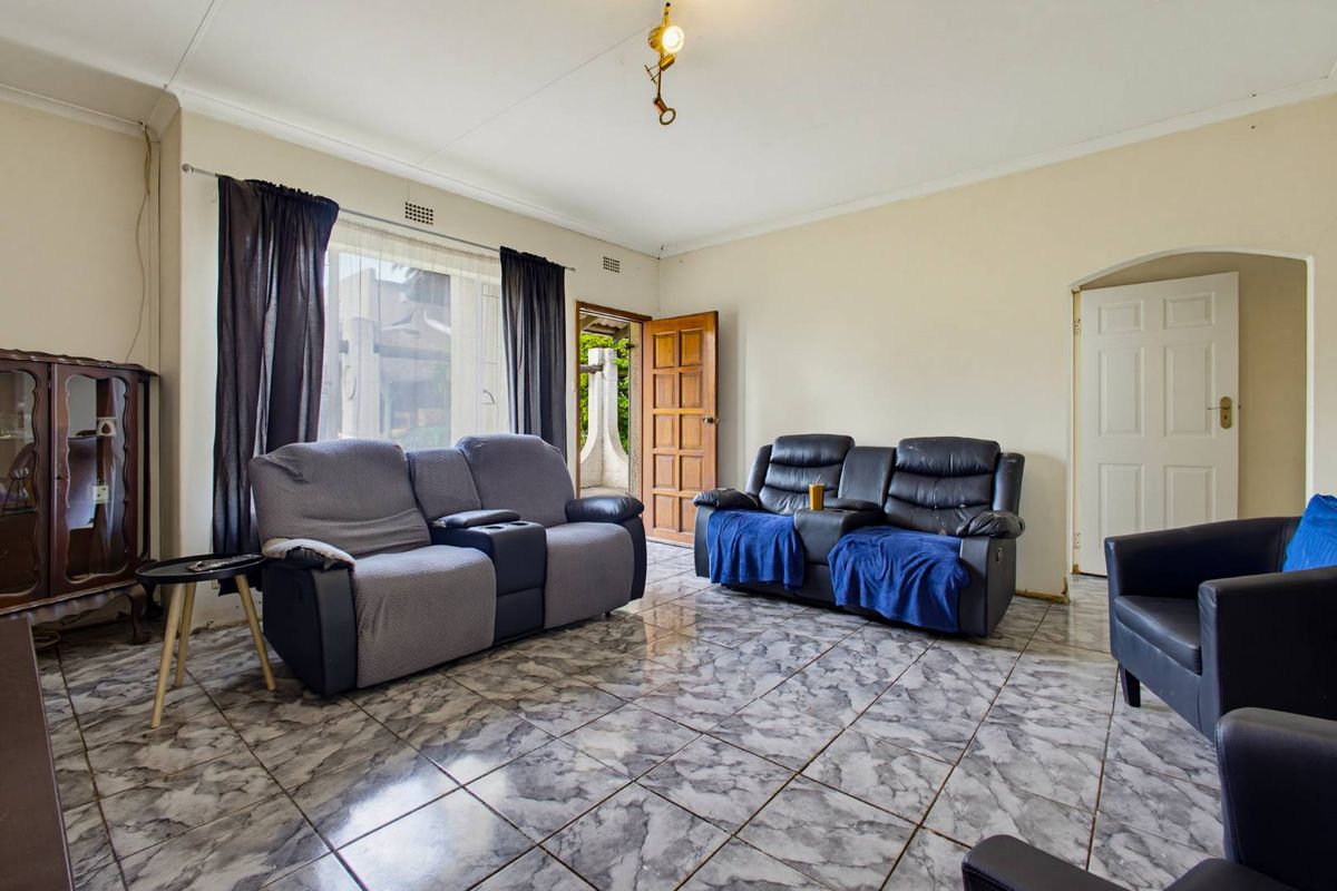 A living room featuring tiled flooring, an arched doorway, and direct access to an outdoor area, offering a functional space ready for modernization.