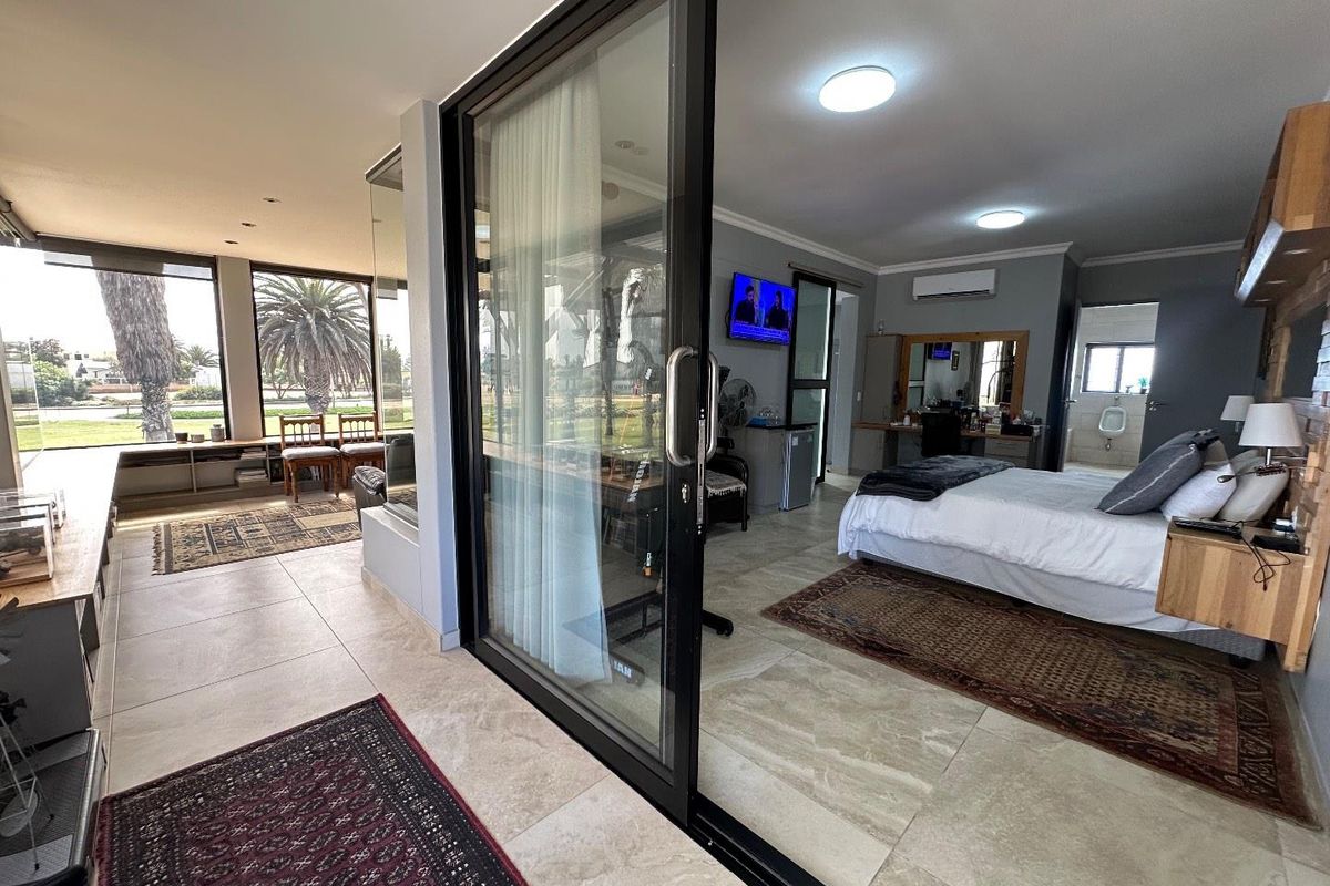 Spacious bedroom featuring large sliding glass doors, tiled flooring, recessed lighting, and an en-suite bathroom with a visible urinal.