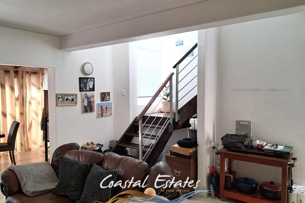 Living area featuring a modern staircase with wooden treads and stainless steel balustrades, leading to an upper level.