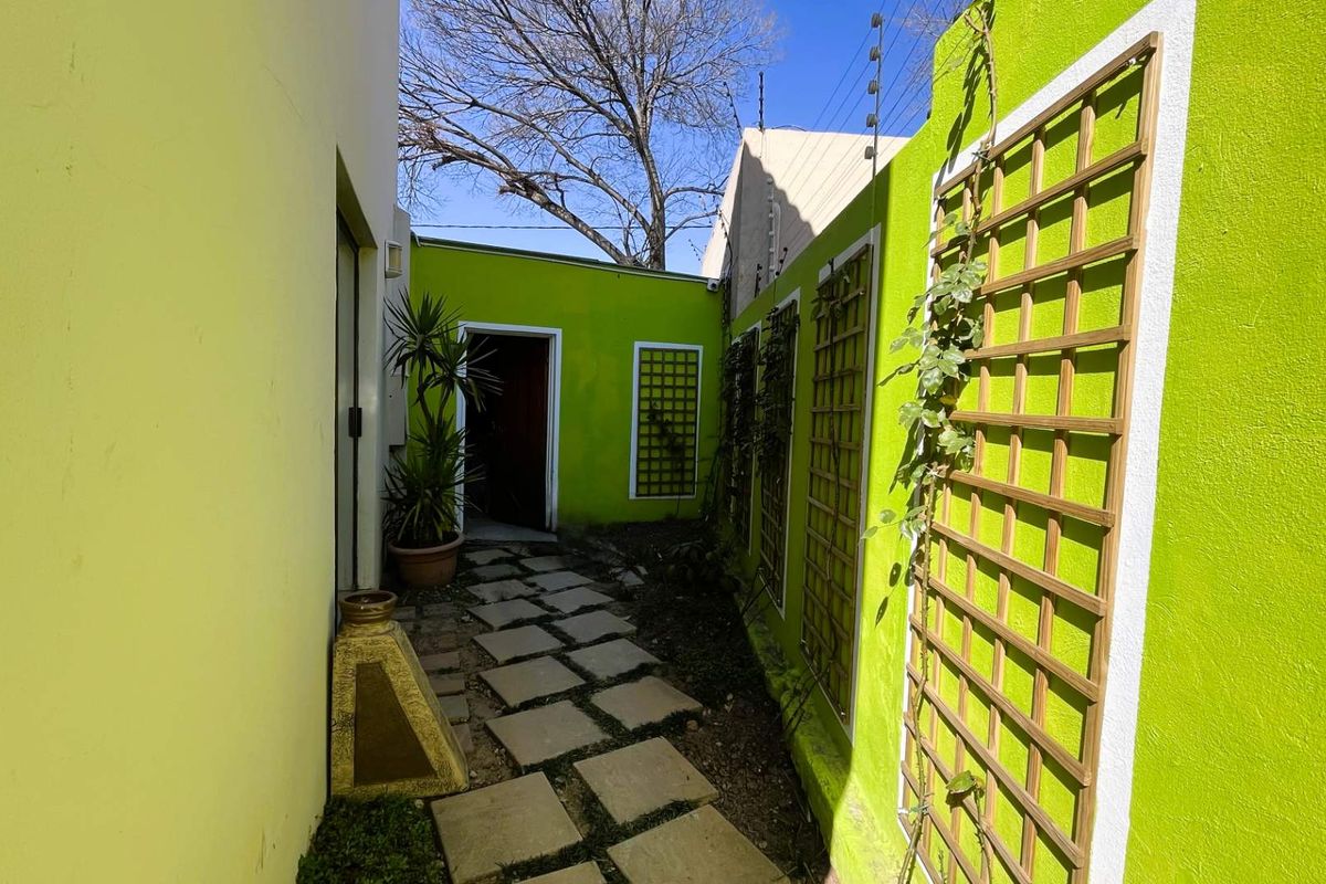 A narrow rear courtyard area featuring stone paving, boundary walls with trellis panels, and electric fencing.