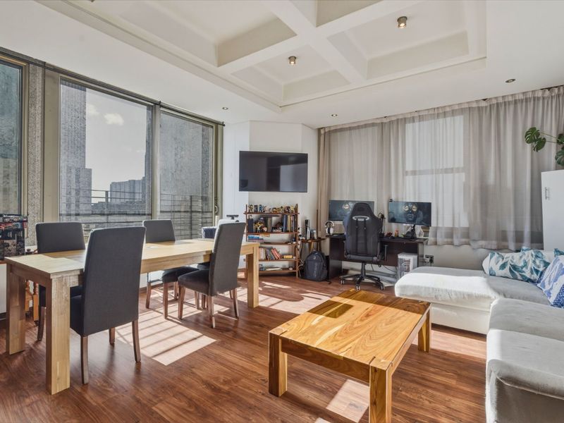 Spacious open-plan living and dining area featuring modern laminate flooring, a distinctive coffered ceiling with recessed lighting, and large sliding doors providing ample natural light.