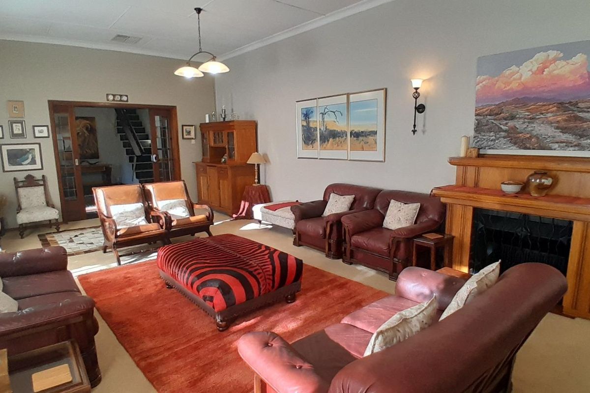 Spacious living room featuring a prominent wooden fireplace mantel, high ceilings, and double glass-paneled doors leading to an internal staircase.