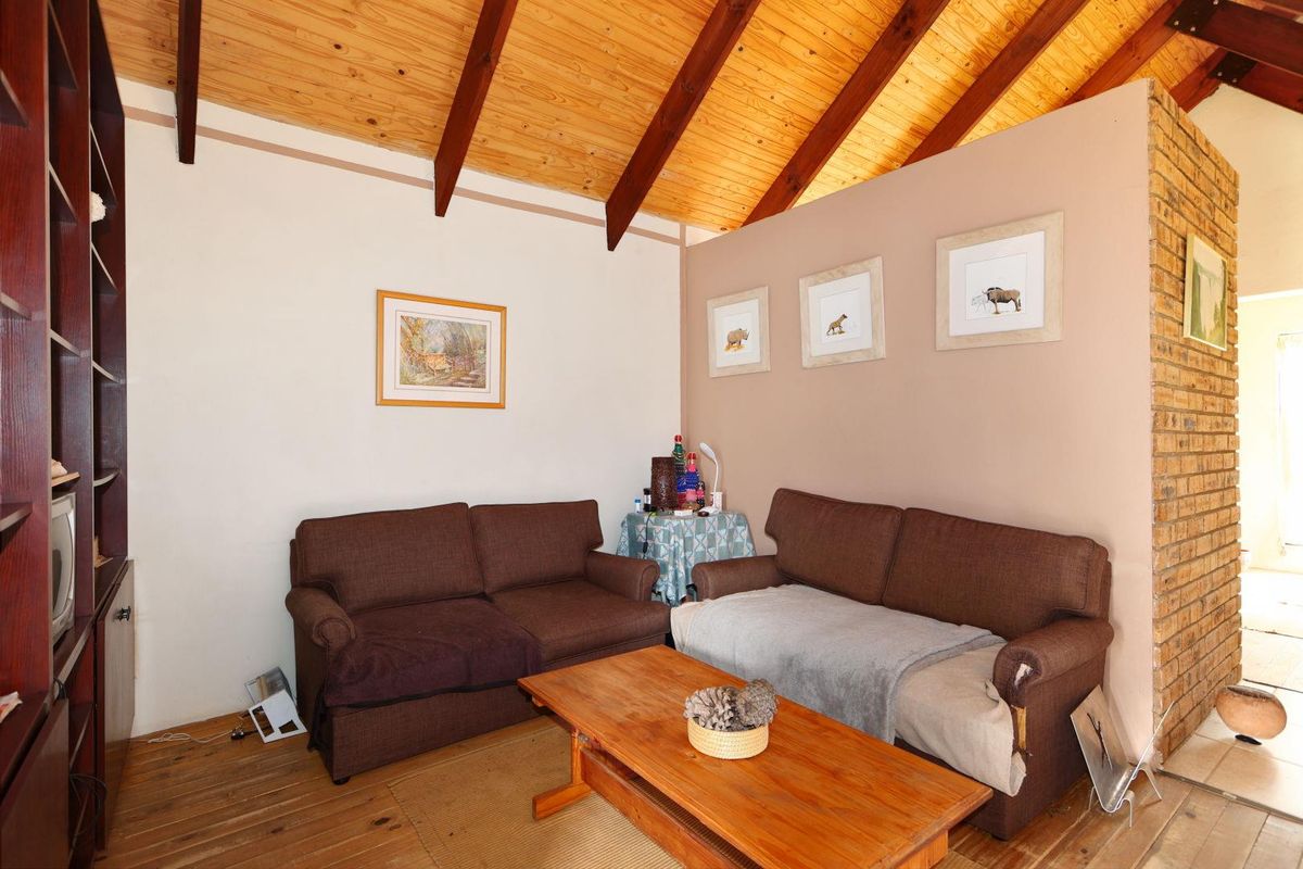 A cozy living room featuring a high vaulted timber ceiling with exposed beams and rustic wooden flooring.