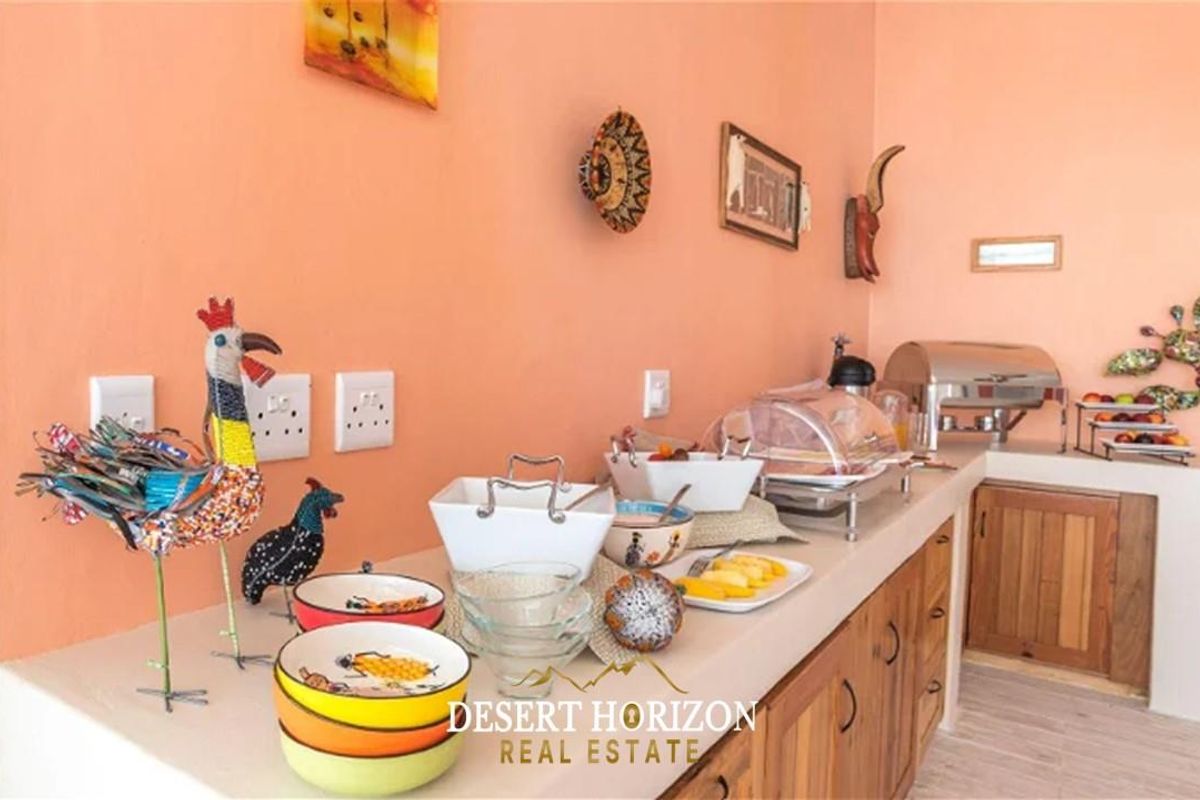 A functional kitchen area featuring built-in cabinetry with wooden doors and a solid countertop, suitable for food preparation and service.