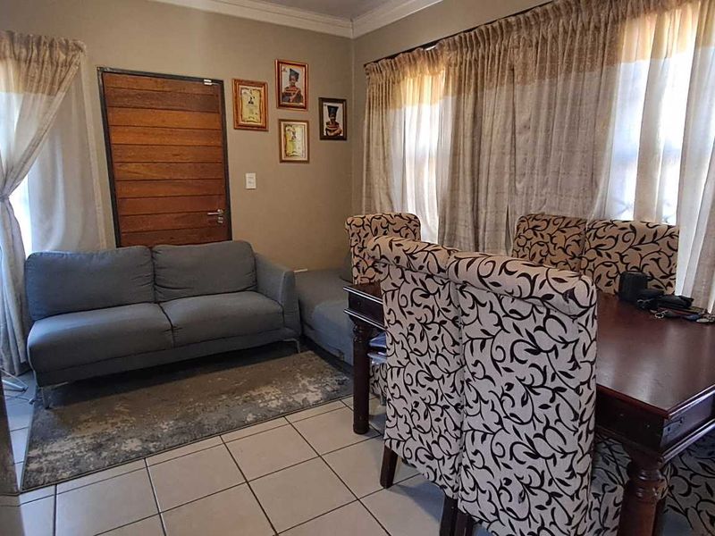 An open-plan living and dining area featuring tiled flooring and neutral wall tones, providing a functional space for daily living and entertaining.
