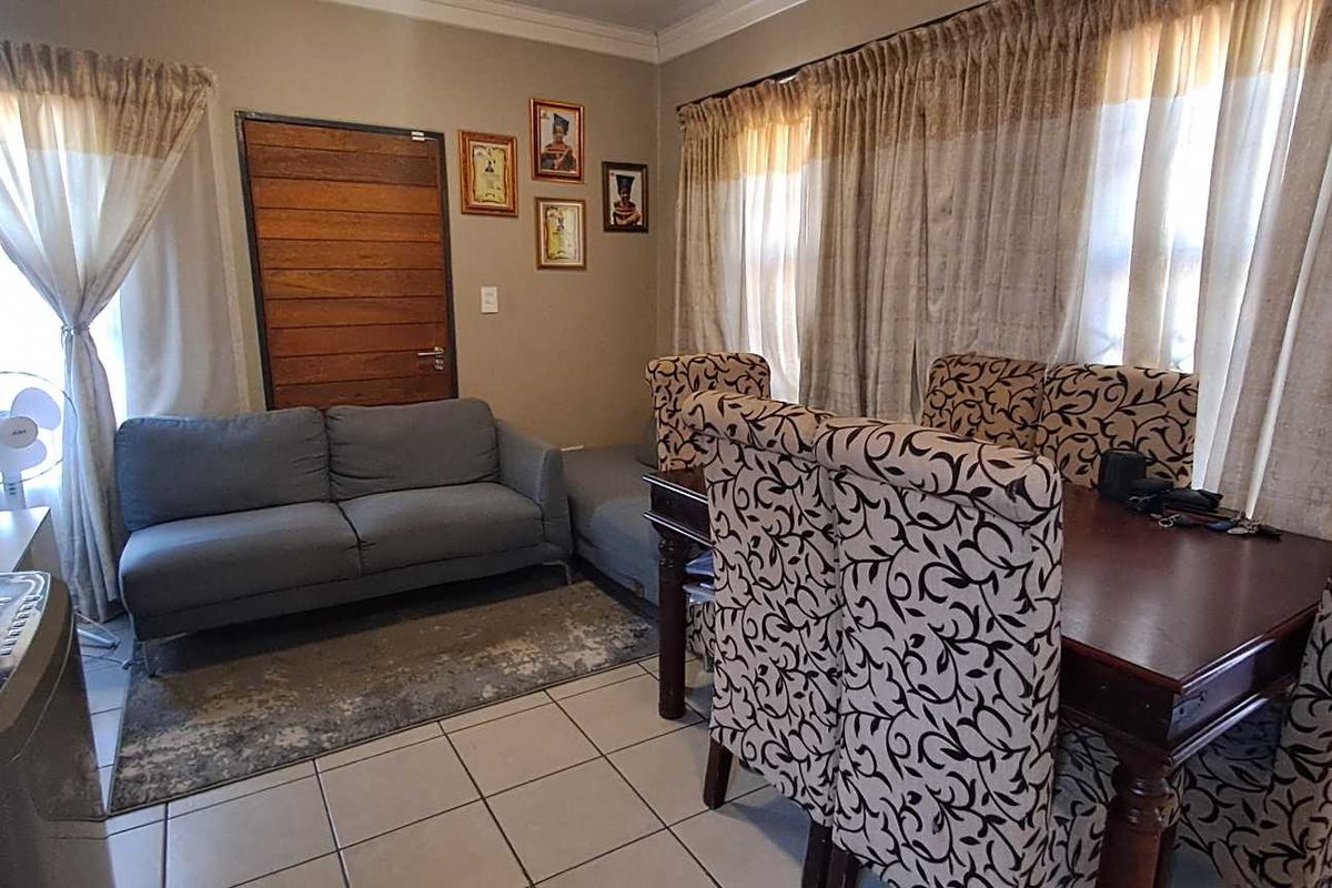 An open-plan living and dining area featuring tiled flooring and neutral wall tones, providing a functional space for daily living and entertaining.