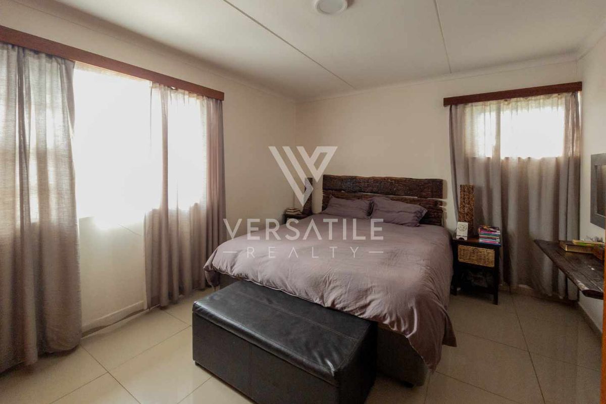 A well-lit bedroom featuring neutral tiled flooring and dual windows with curtain rods.