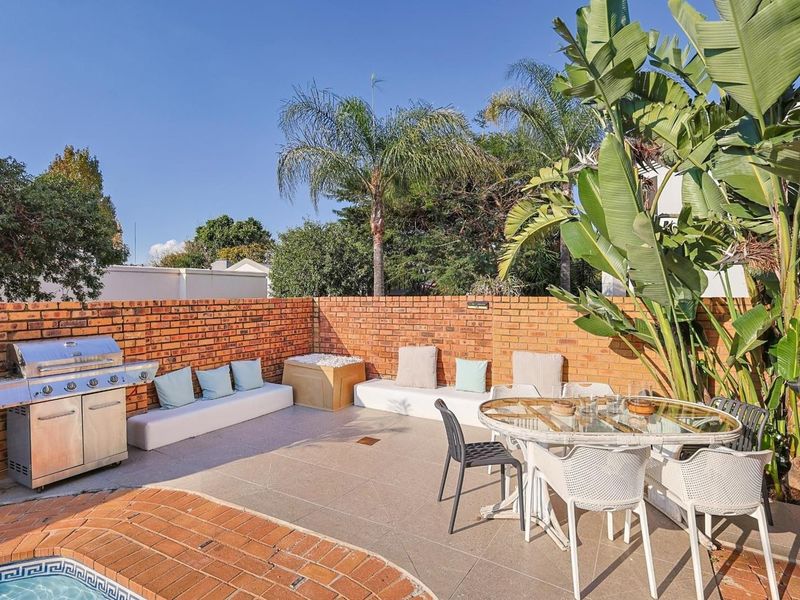 Outdoor patio area featuring built-in brick walls, tiled flooring, and integrated seating, adjacent to a swimming pool.