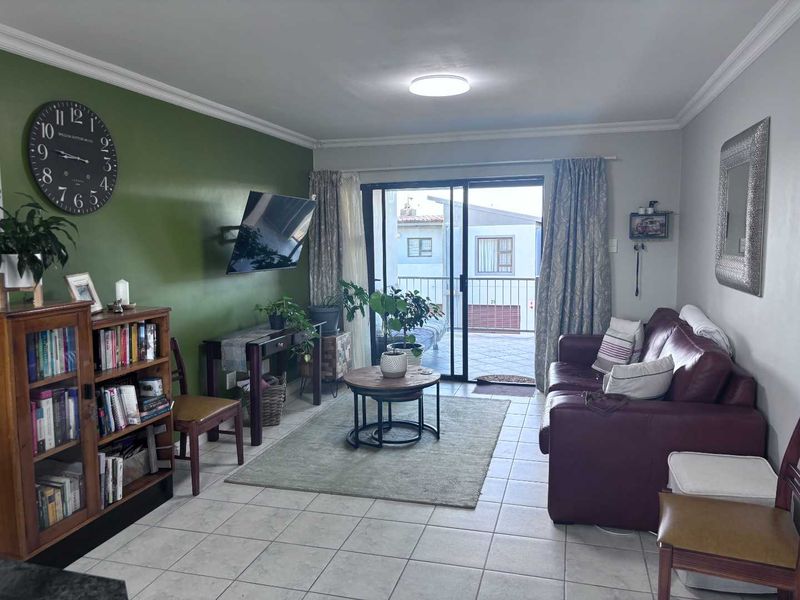 A comfortable living room featuring tiled flooring, a feature wall, and sliding glass doors that provide direct access to an outdoor balcony area.