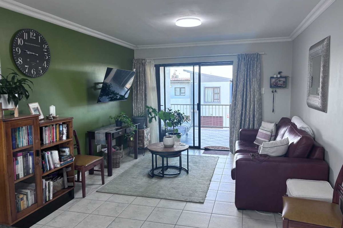 A comfortable living room featuring tiled flooring, a feature wall, and sliding glass doors that provide direct access to an outdoor balcony area.