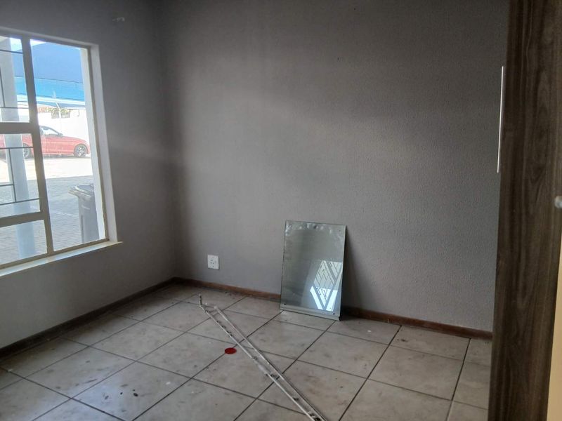 An empty bedroom featuring tiled flooring and a large window, providing a blank canvas for potential interior design and renovation.