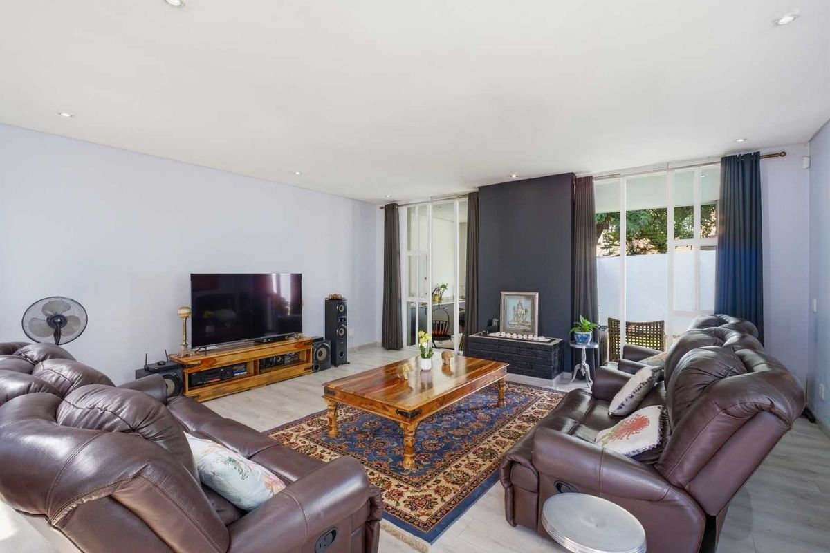 Spacious living room featuring a dark accent wall with a built-in fireplace, recessed lighting, and large glass doors leading to an outdoor area.
