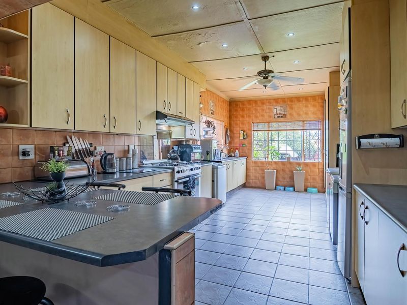 Spacious kitchen featuring extensive built-in cabinetry, tiled flooring, and a breakfast bar, offering a functional layout with potential for modern updates.