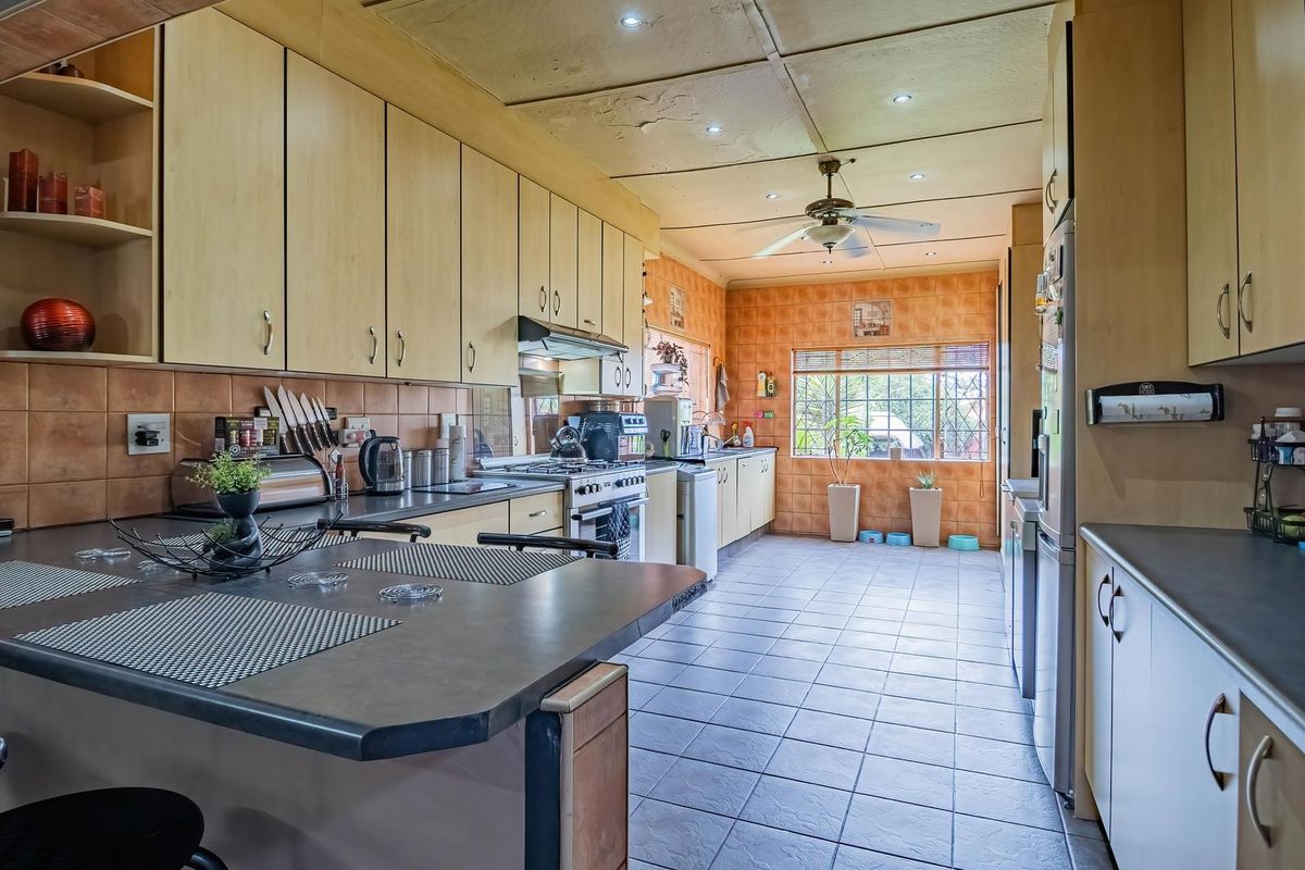 Spacious kitchen featuring extensive built-in cabinetry, tiled flooring, and a breakfast bar, offering a functional layout with potential for modern updates.