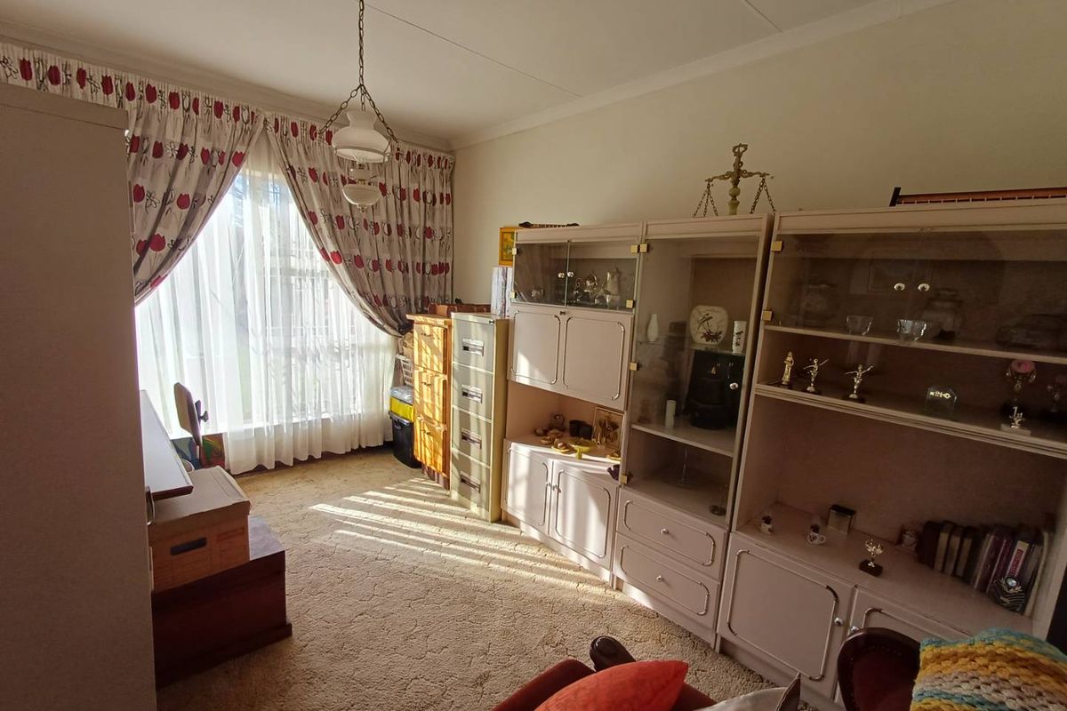 A bedroom featuring carpeted flooring, large window with curtains, and a central pendant light fixture.