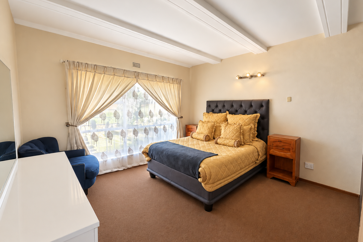 A well-maintained bedroom featuring carpeted flooring, decorative ceiling beams, and a wall-mounted light fixture, offering a comfortable and functional living space.