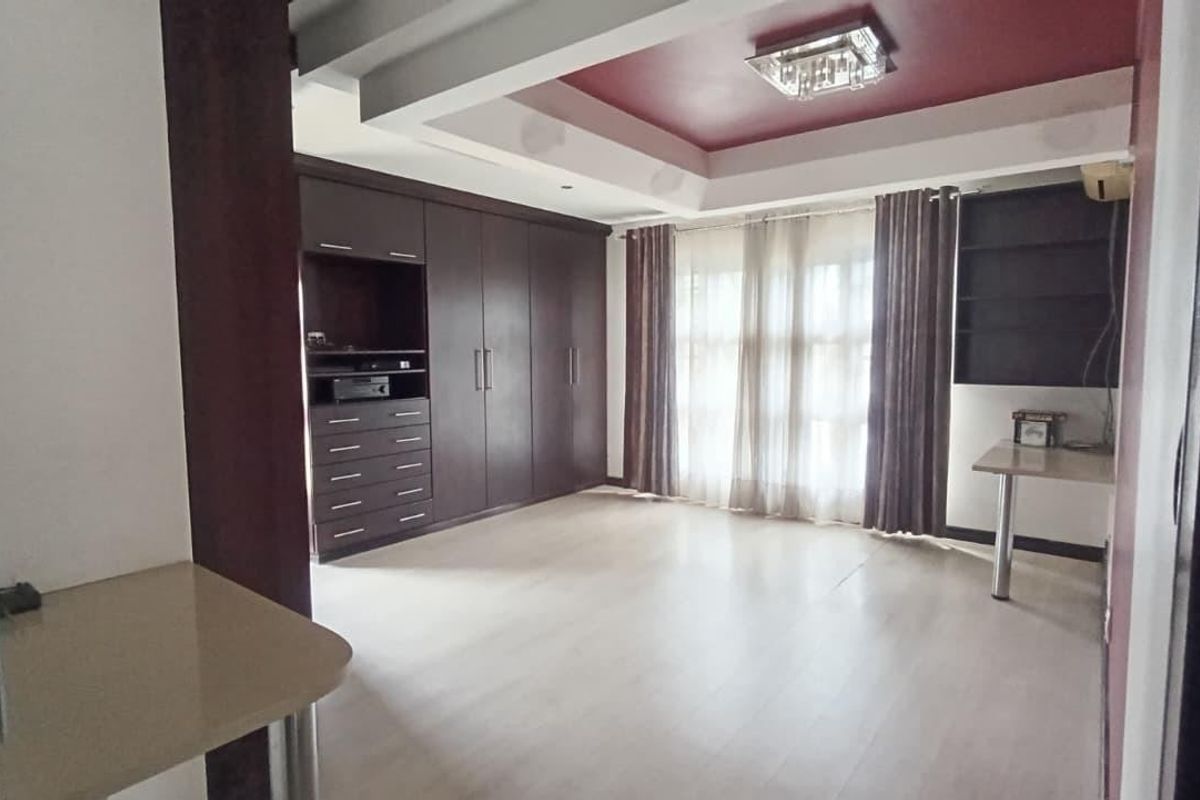 Spacious bedroom featuring extensive built-in cabinetry, a built-in desk, and a decorative tray ceiling with recessed lighting.