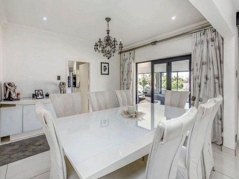 A bright and spacious dining room featuring tiled flooring, recessed downlights, and large sliding glass doors that provide access to the outdoor area.