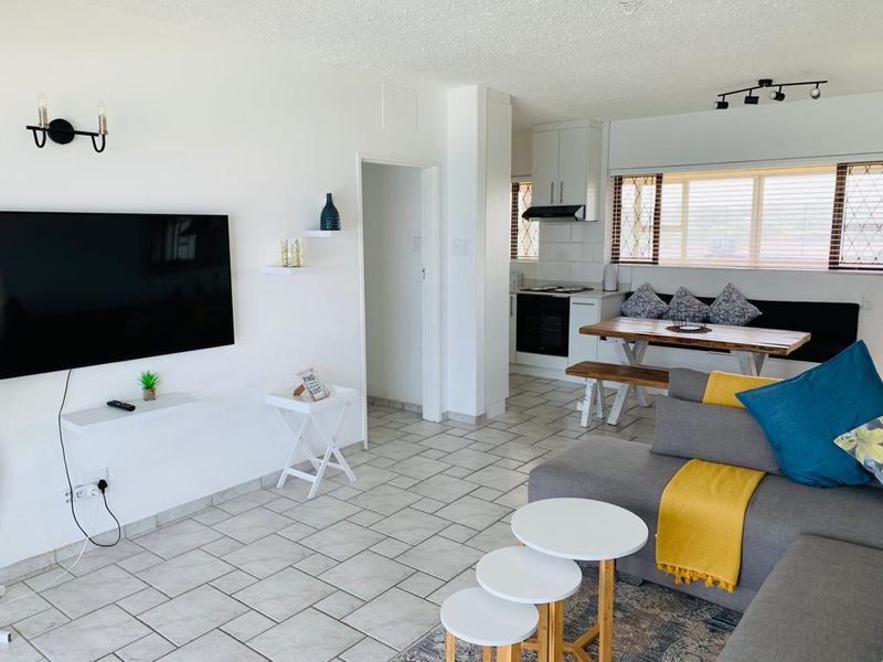 Open-plan living and kitchen area featuring tiled flooring, modern cabinetry, built-in oven, hob, and extractor fan, creating a bright and functional living space.