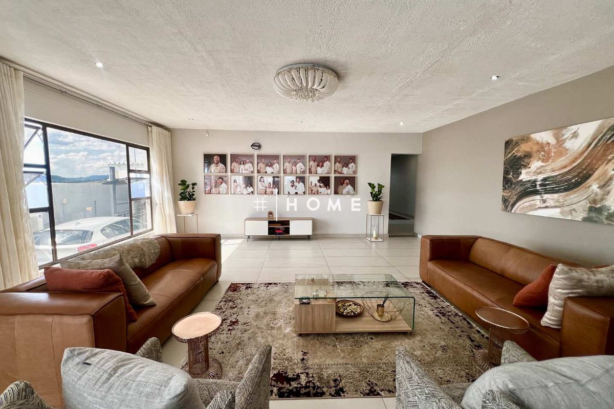 Spacious living room featuring large windows, tiled flooring, and modern recessed lighting, creating a bright and inviting atmosphere.