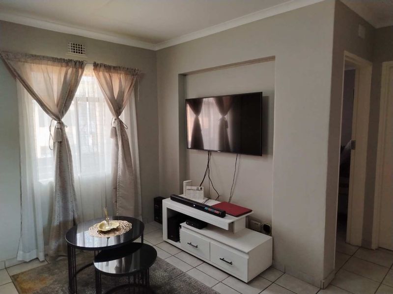 A living room featuring a recessed wall niche for media equipment and tiled flooring, providing a functional and neutral living space.