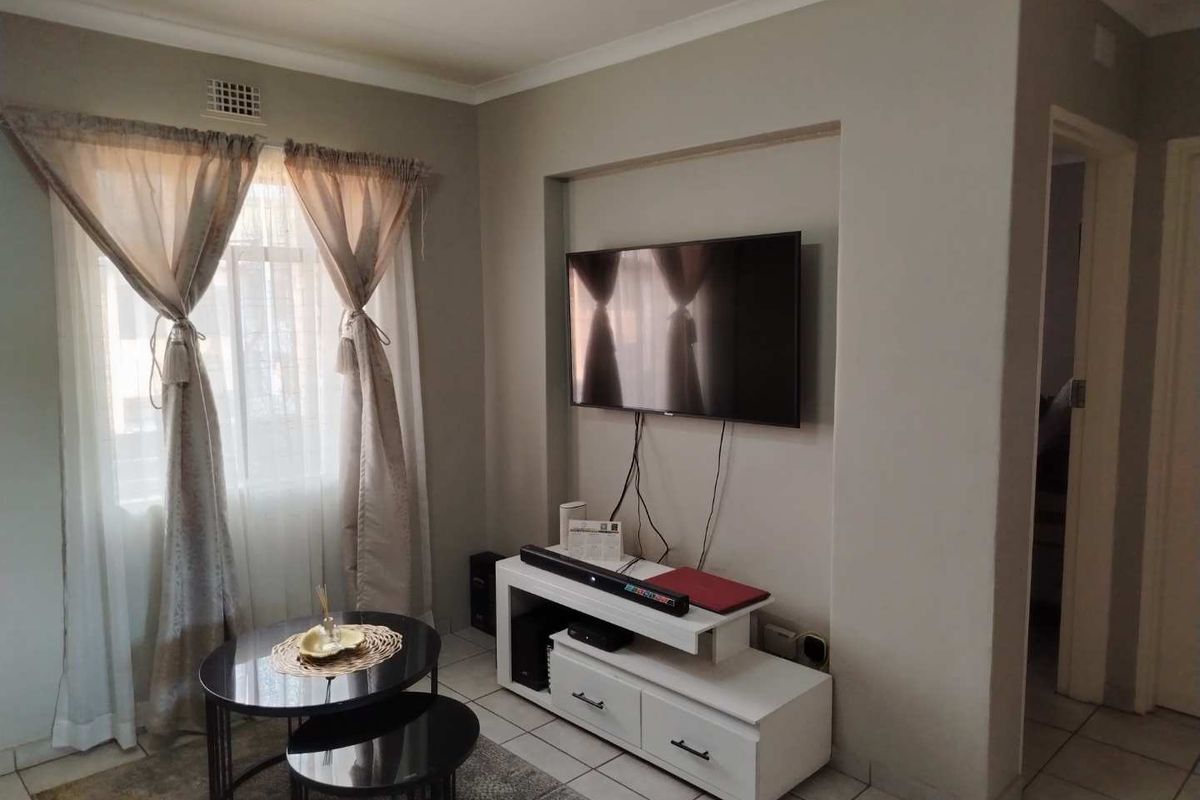 A living room featuring a recessed wall niche for media equipment and tiled flooring, providing a functional and neutral living space.