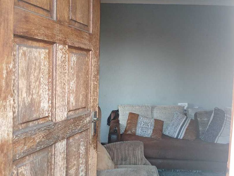 A view into a living room area featuring a weathered timber door in the foreground.