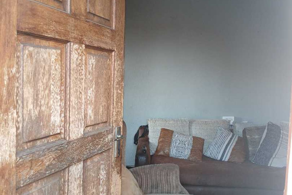 A view into a living room area featuring a weathered timber door in the foreground.