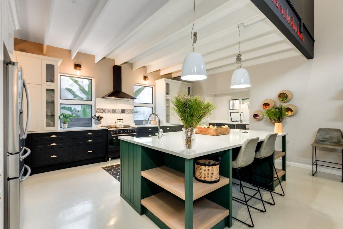Modern kitchen featuring a large central island with stone countertops, custom cabinetry, exposed beam ceiling, and high-end built-in appliances.