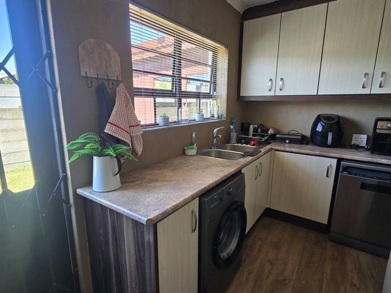 Compact kitchen featuring laminate countertops, double bowl sink, built-in cabinetry, and direct access to the exterior via a security gate.