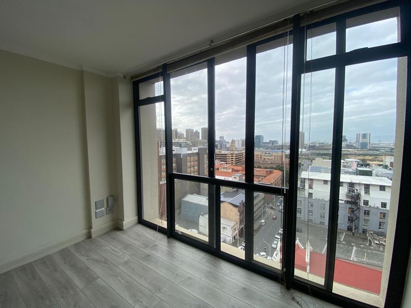 Bright and modern living area featuring floor-to-ceiling windows with expansive city views and durable laminate flooring.