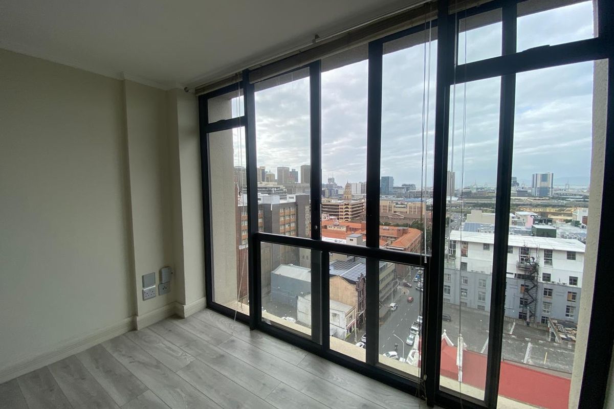 Bright and modern living area featuring floor-to-ceiling windows with expansive city views and durable laminate flooring.