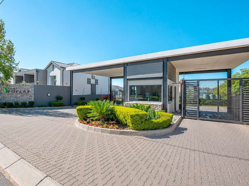 The secure entrance gate and guard house of The 10 Poplar estate, featuring modern architectural design, stone accents, and well-maintained paved access.