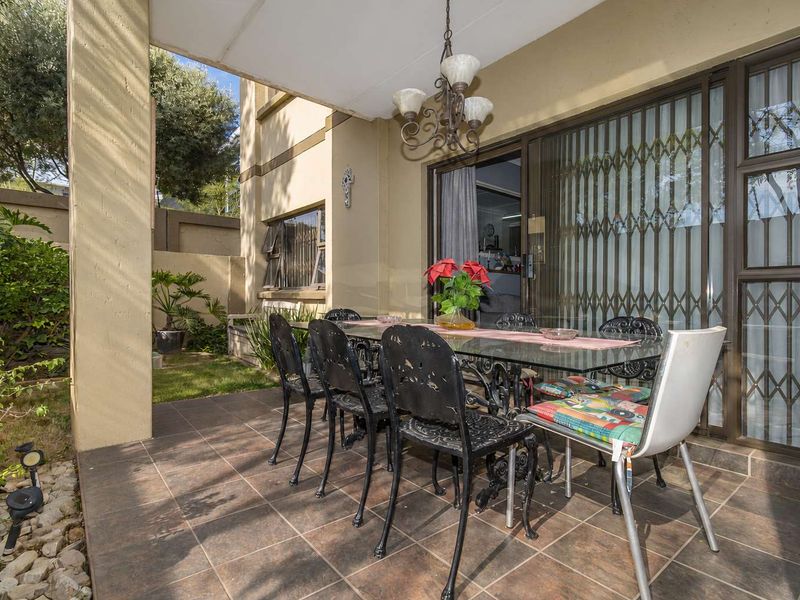 A covered patio area featuring tiled flooring and direct access to the interior through sliding glass doors with security gates.