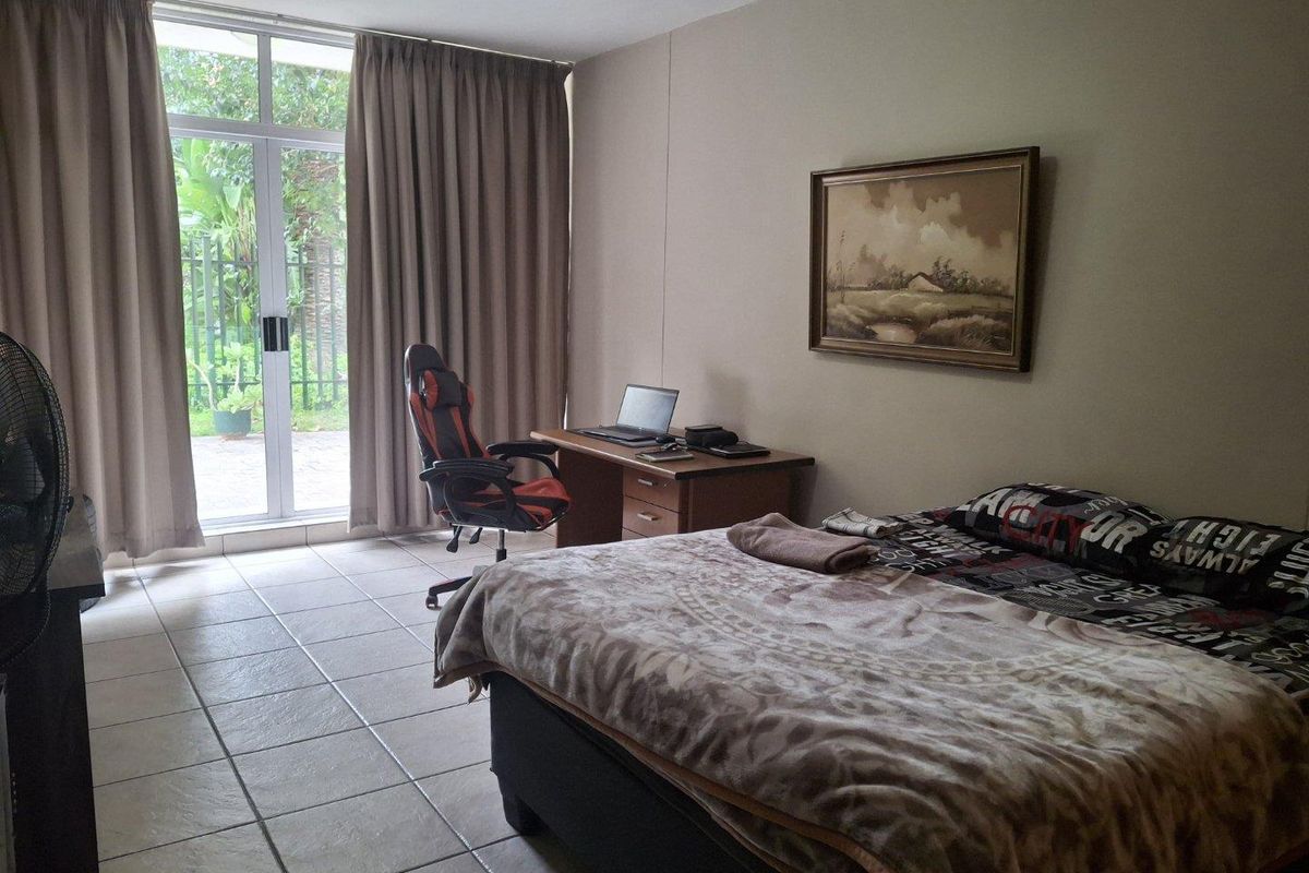 A bedroom featuring tiled flooring and a sliding glass door providing access to the outdoor area.