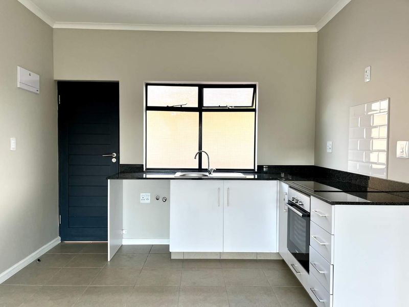 Modern kitchen featuring granite countertops, built-in oven, hob, subway tile backsplash, and ample cabinetry in a clean, neutral space.