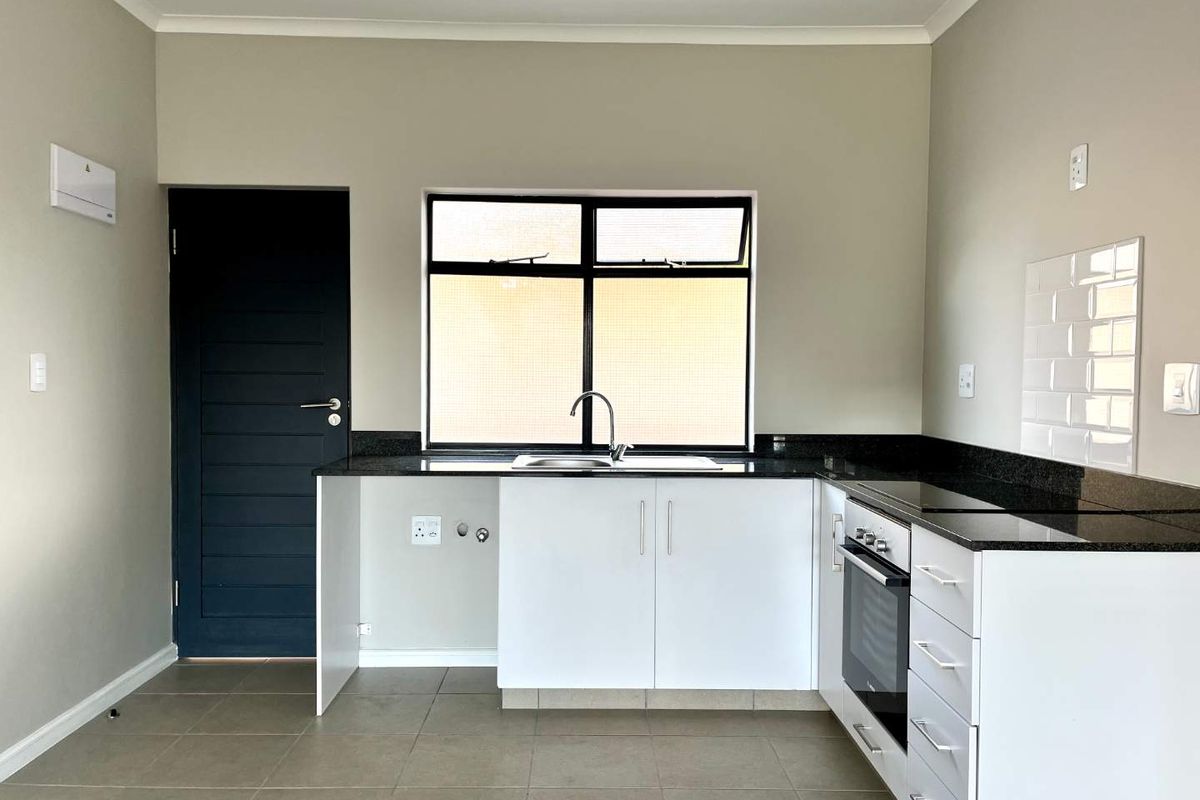 Modern kitchen featuring granite countertops, built-in oven, hob, subway tile backsplash, and ample cabinetry in a clean, neutral space.