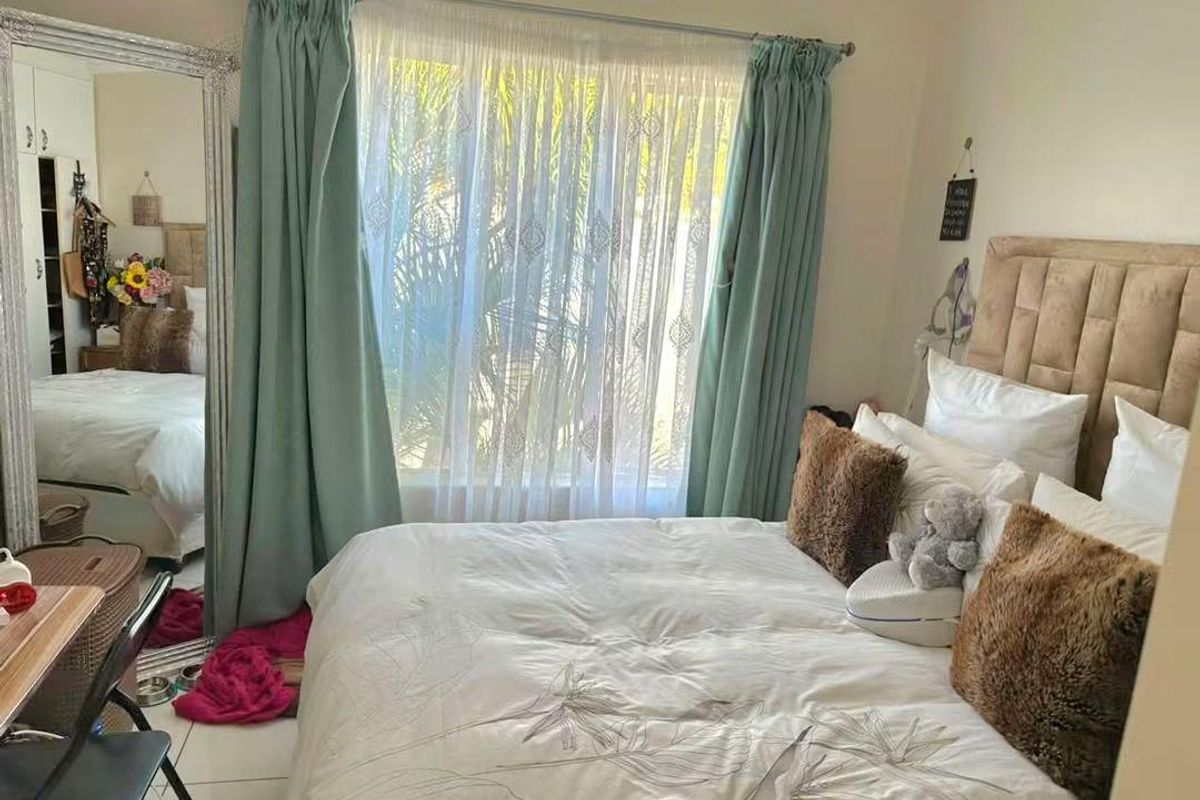 A bedroom featuring tiled flooring, a built-in wardrobe, and a window dressed with curtains, providing a functional living space.