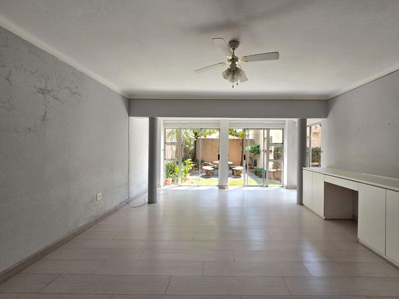 Spacious open-plan living area featuring laminate flooring, built-in cabinetry, and large sliding glass doors providing direct access to the rear garden.
