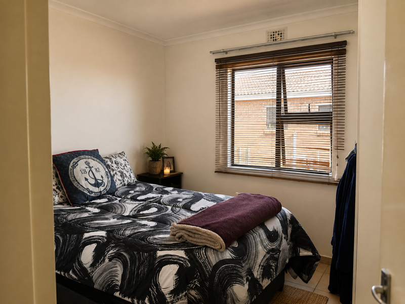 A cozy bedroom featuring tiled flooring and timber venetian blinds, offering a functional and comfortable living space.
