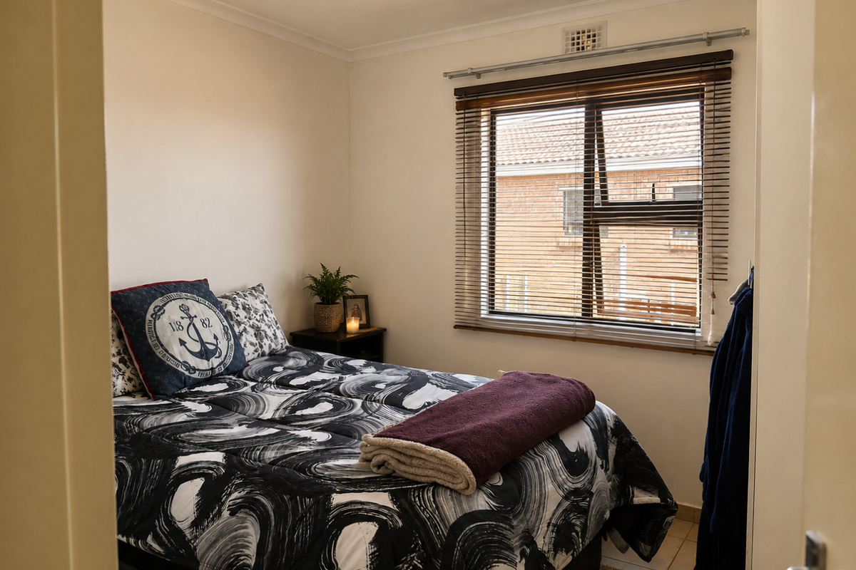 A cozy bedroom featuring tiled flooring and timber venetian blinds, offering a functional and comfortable living space.