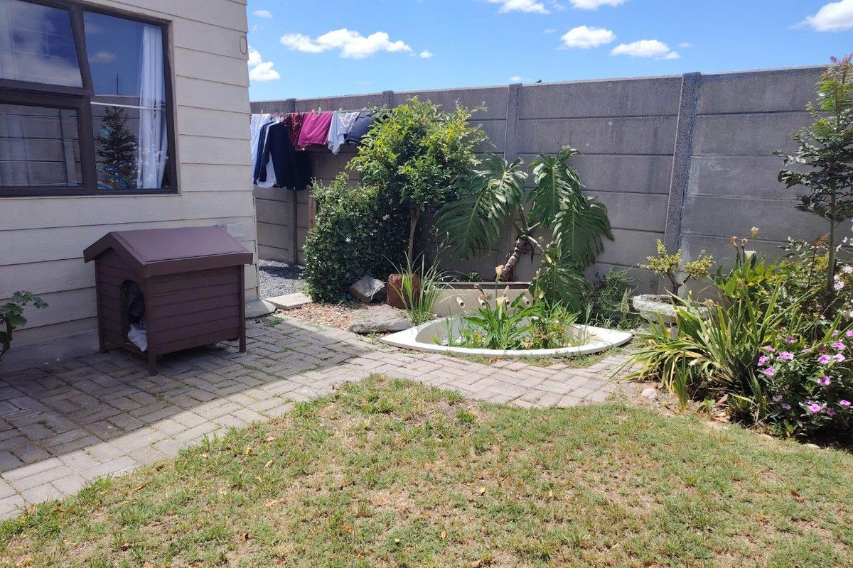 A rear garden area featuring a paved patio, a sunken pond, and a precast concrete boundary wall.