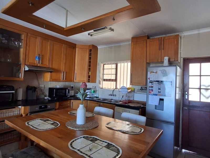 A functional kitchen featuring wooden cabinetry, built-in oven, extractor fan, and a double sink, with a recessed ceiling feature and direct exterior access.