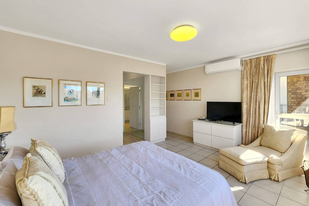 A bedroom featuring tiled flooring, built-in shelving, a split-system air conditioner, and direct access to an outdoor balcony area.