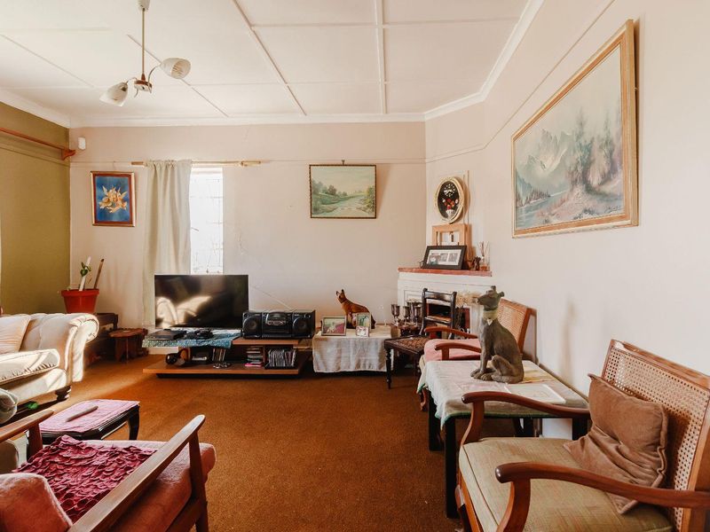 A living room featuring a fireplace and tiled ceiling, showing signs of wear including visible wall cracks.