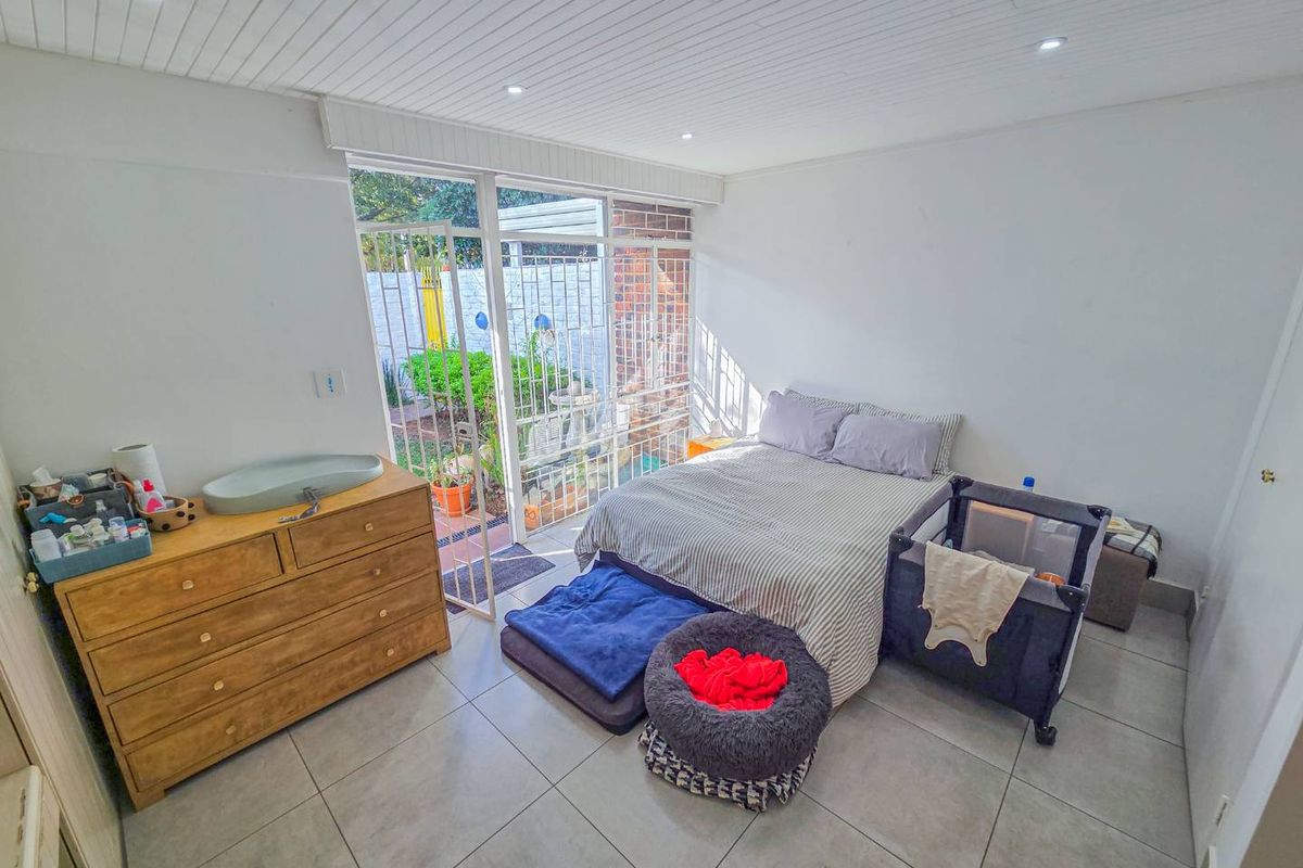 A bedroom featuring tiled flooring, recessed lighting, and a timber panel ceiling, with direct access to an outdoor area through a sliding glass door.